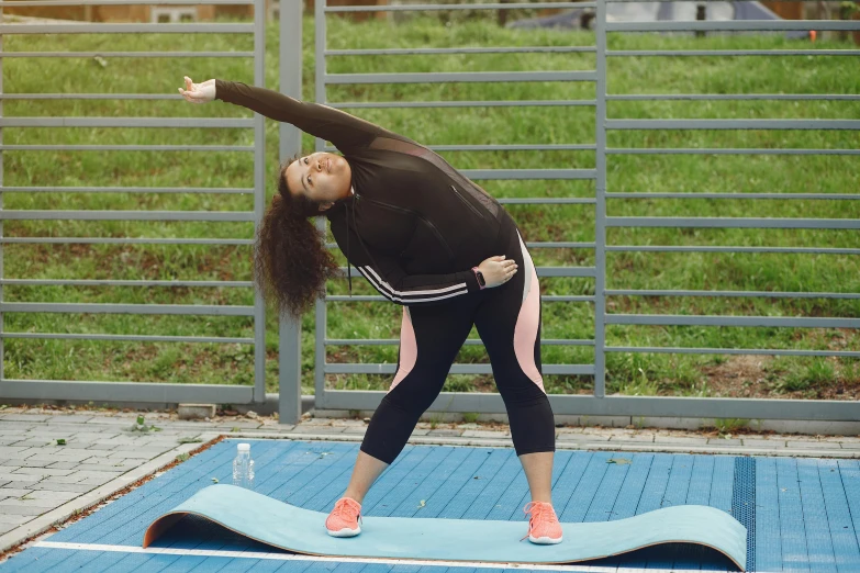 woman in black and pink doing a yoga pose on a blue floor