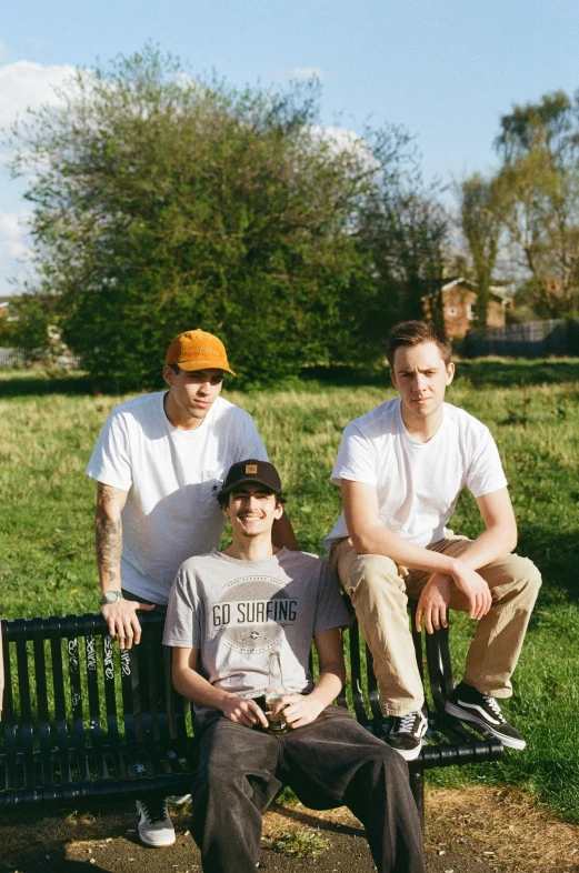 four men are sitting on a bench outside