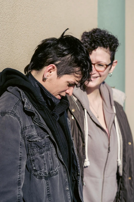 a couple of people standing next to each other near a wall