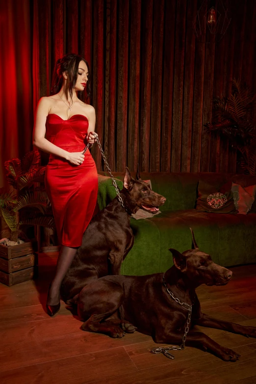 woman in red dress with two dogs on red carpet