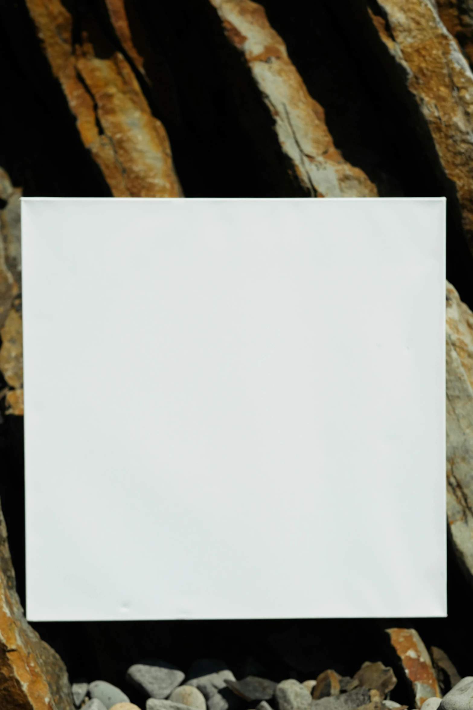 a square white piece of paper on some rocks