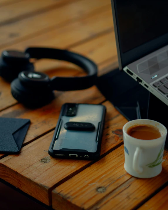 a table with a cup of coffee and phone on it