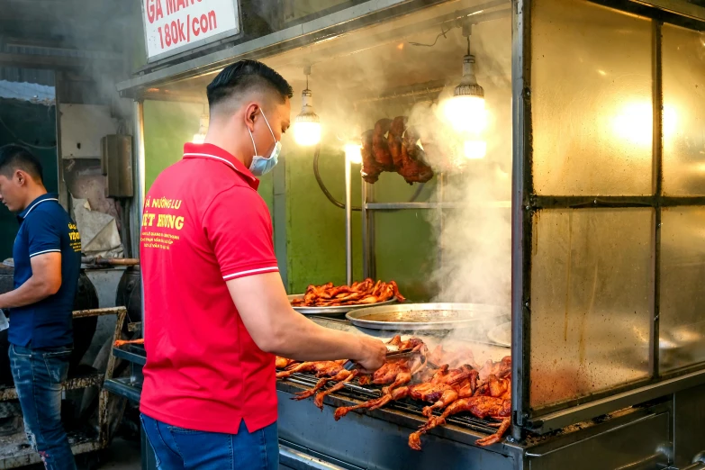 a man grilling chicken in an industrial kitchen