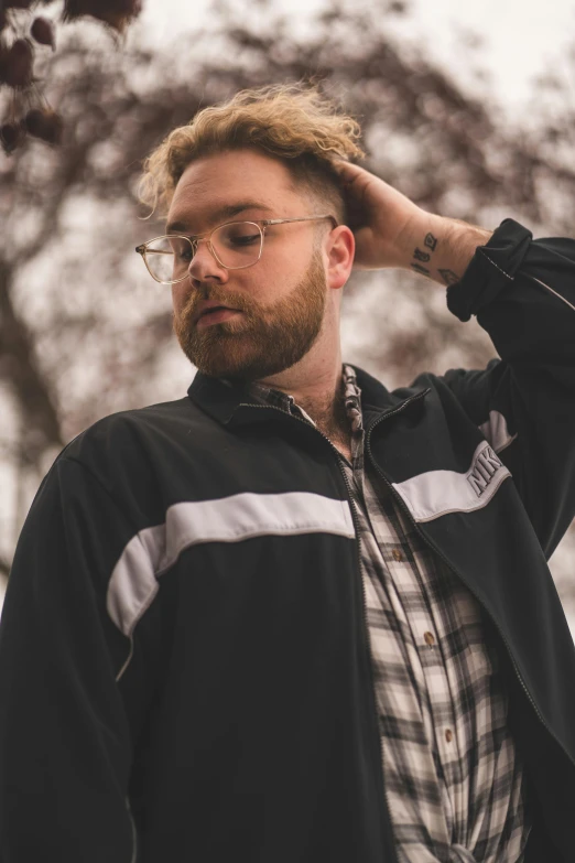 a bearded man is wearing a jacket and glasses