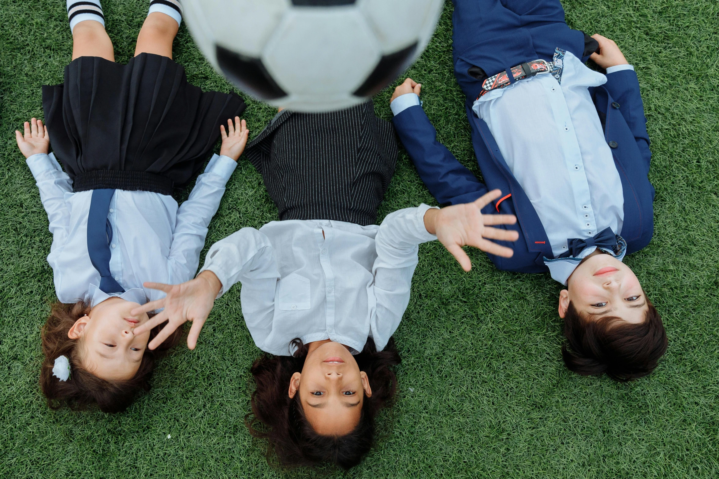 three s are laying on the grass with a soccer ball in their hands