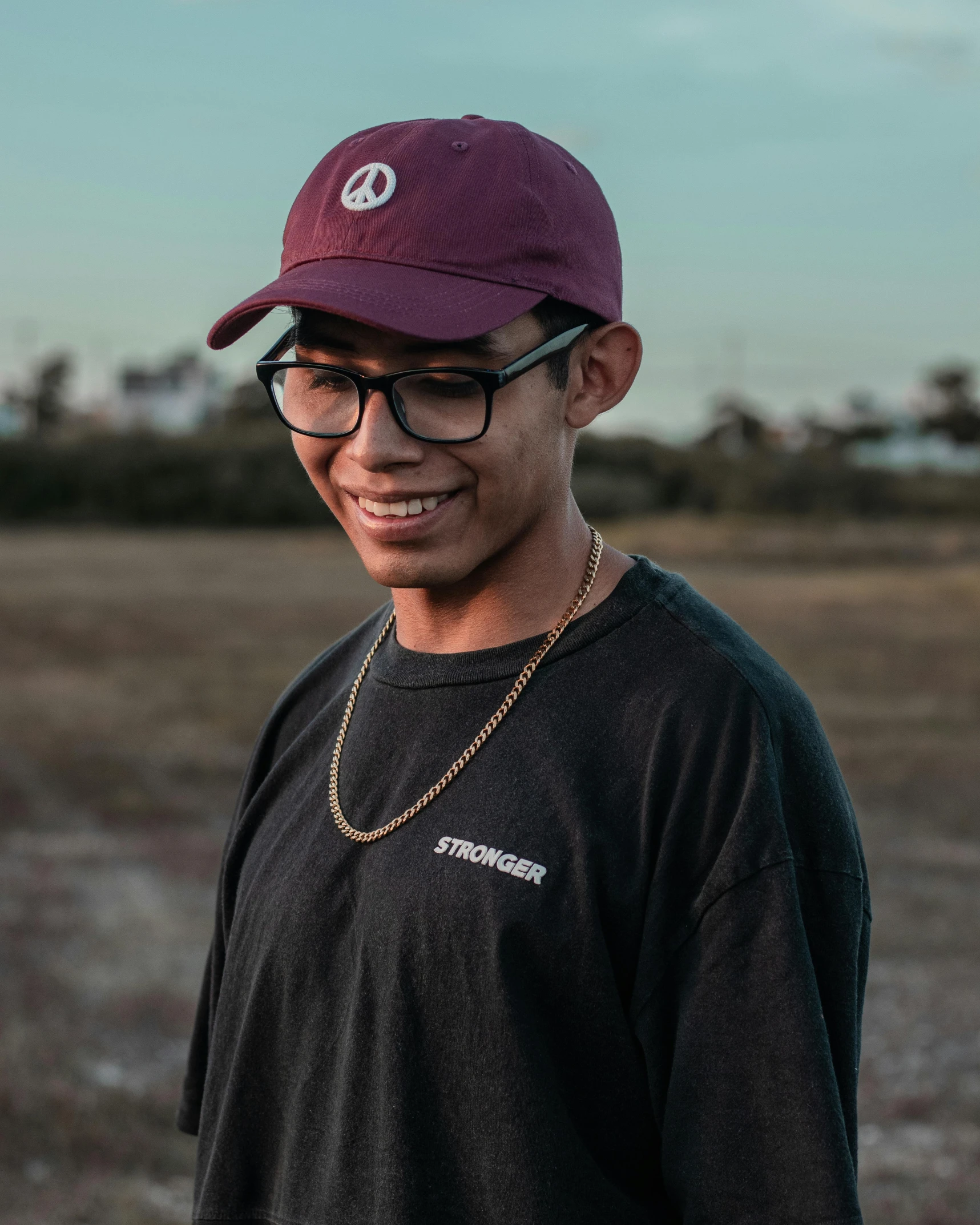 a man with glasses wearing a burgundy hat and black shirt