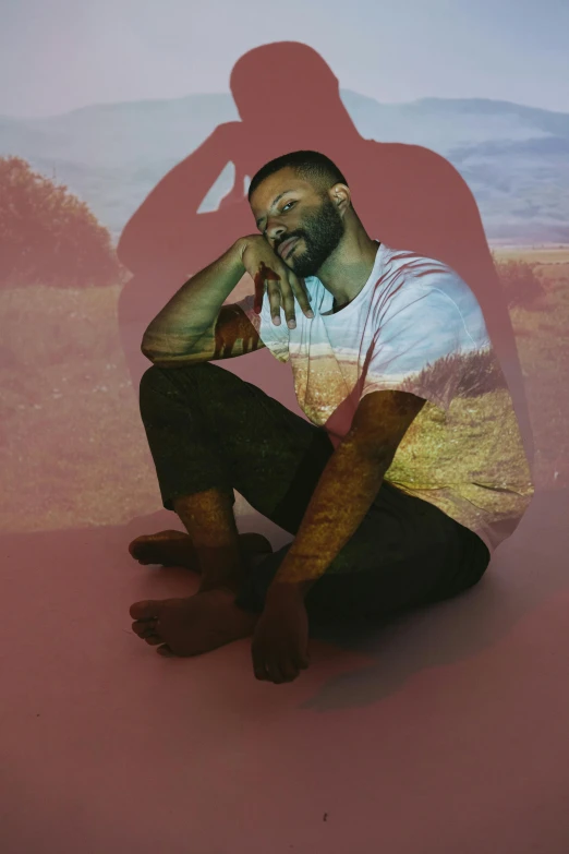 a man kneeling on the ground in front of a red background