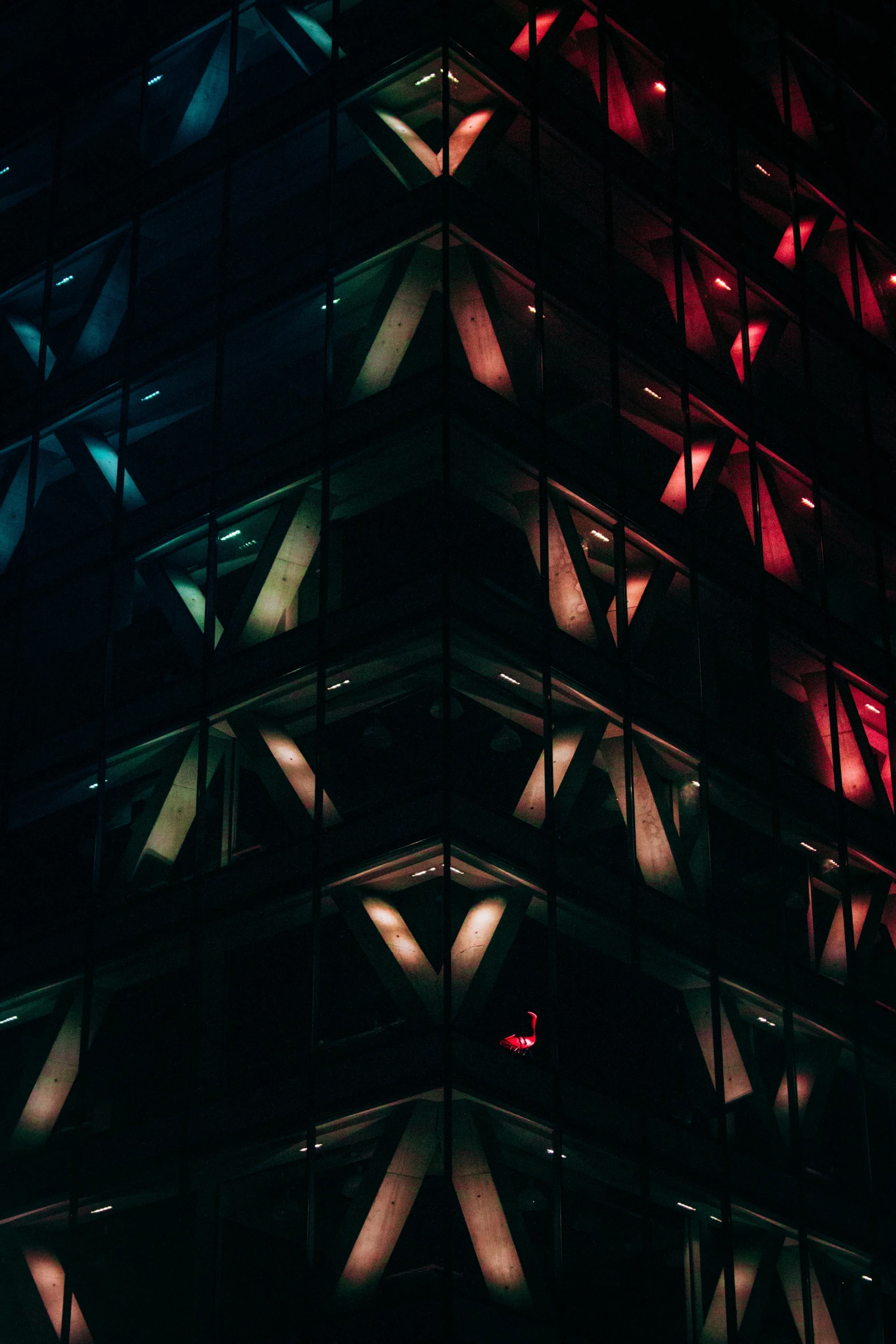 red light is shining in the glass exterior of a tall building