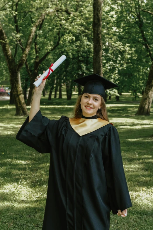 woman graduating in a cap and gown holding a diploma