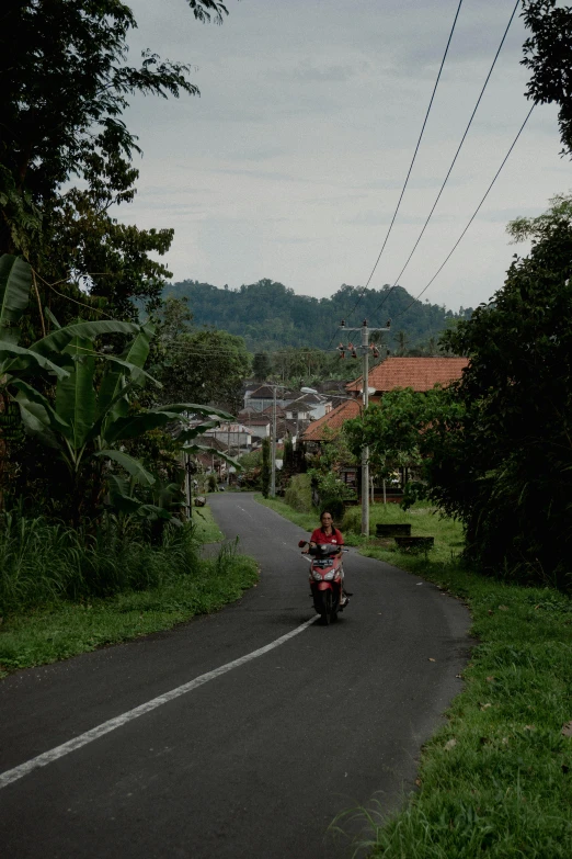 a man riding a motorcycle down a street with power lines over head