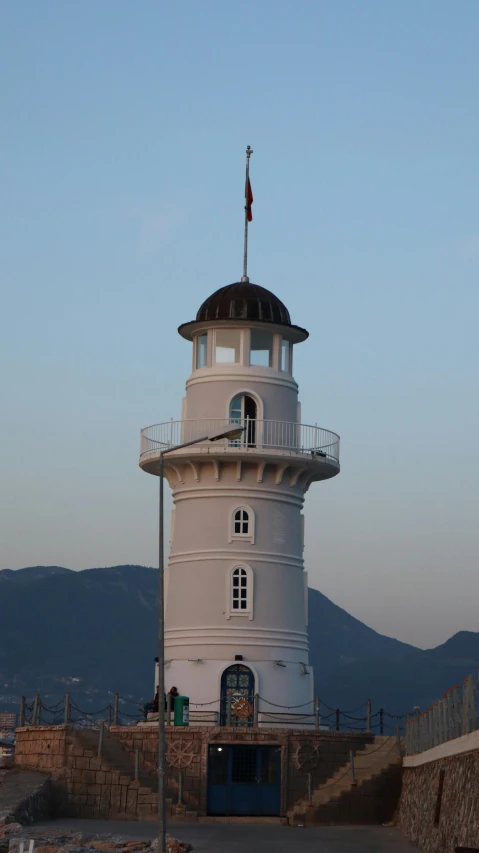 a white light house with two flags on top