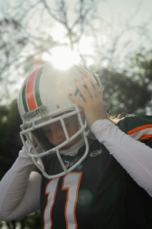 a football player has his hand to his helmet