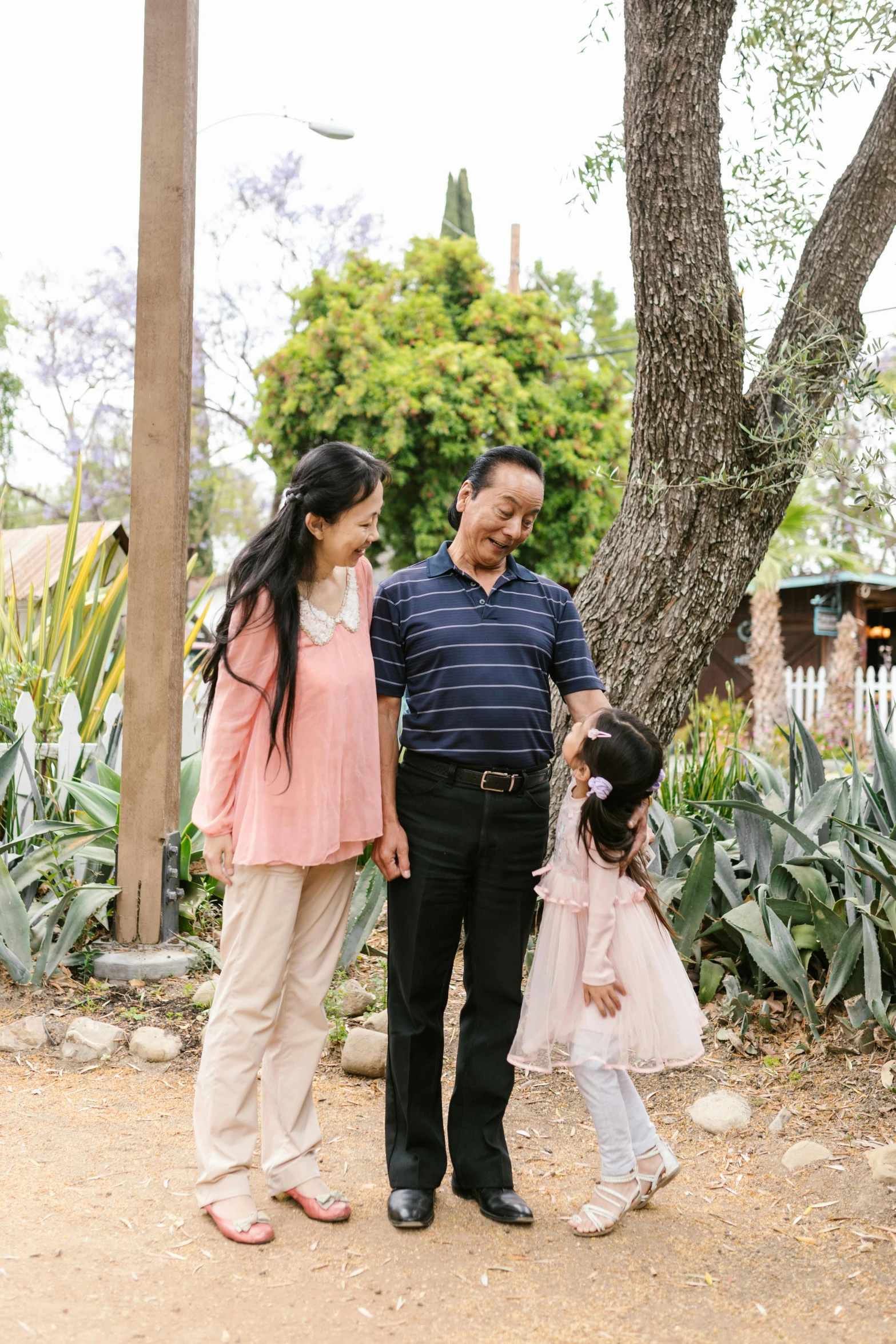 an asian family stands together by the trees