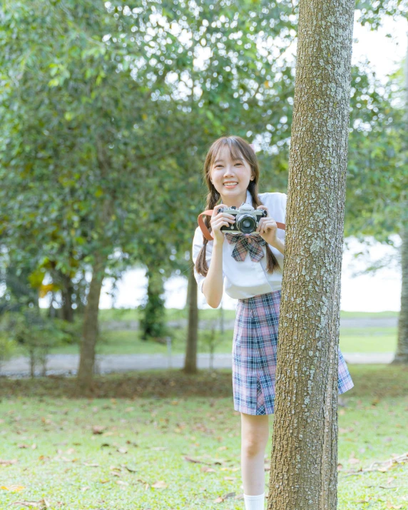 a  holding a camera up against a tree