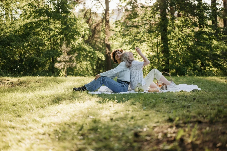 two young women are laying in the grass on the ground