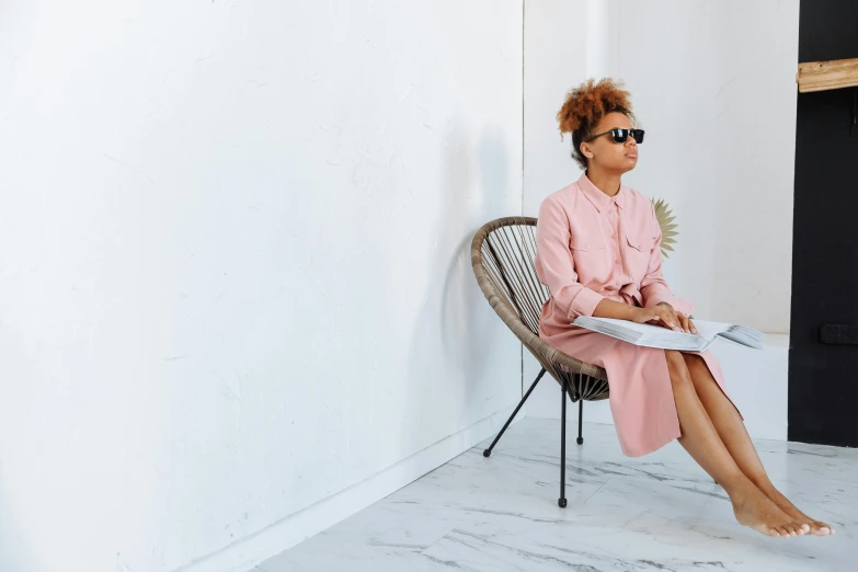 a woman in pink wearing a robe and sunglasses sitting on a chair