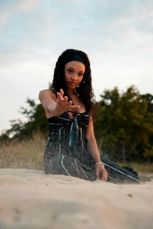 a woman is sitting on the beach and making a hand gesture