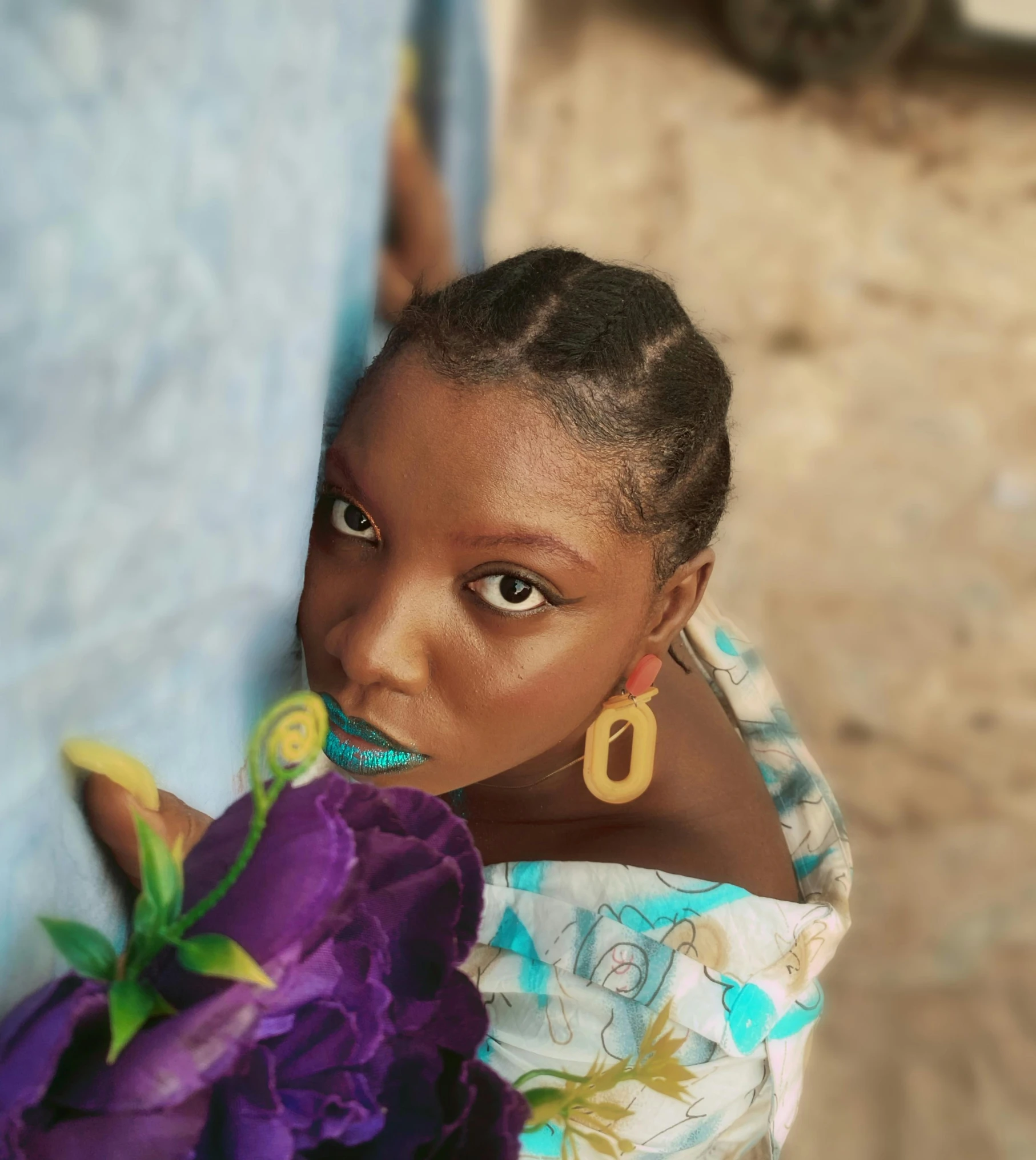 a woman wearing a dress and earrings holding a flower