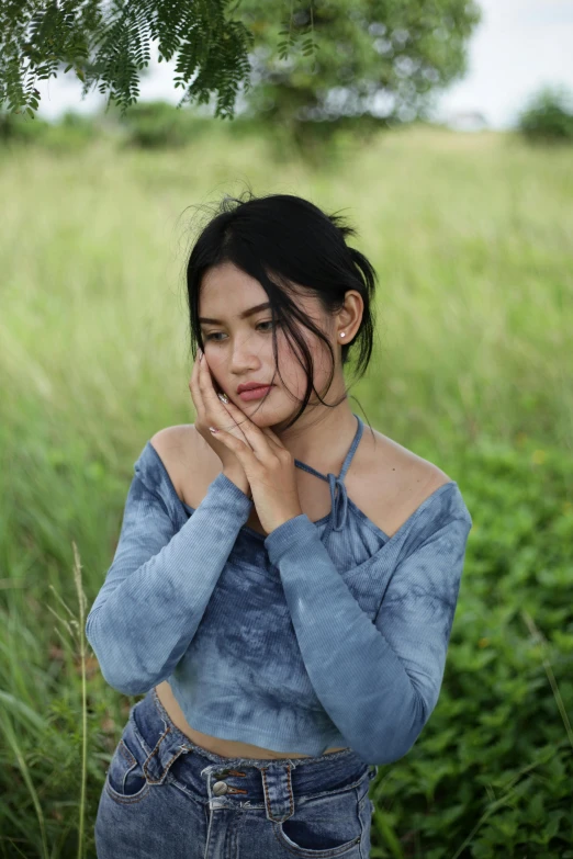 a woman in jeans holding her face to her chest