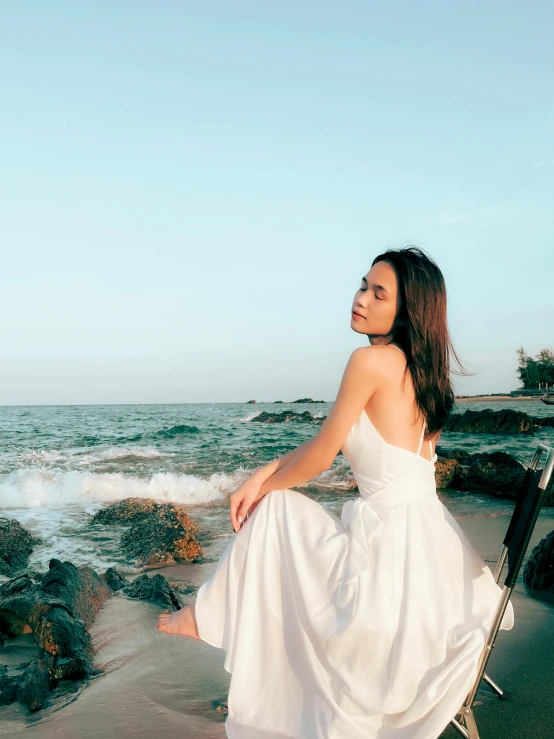 a woman in white dress standing by the ocean
