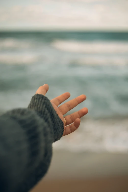 a person with their arm extended open holding soing near the ocean