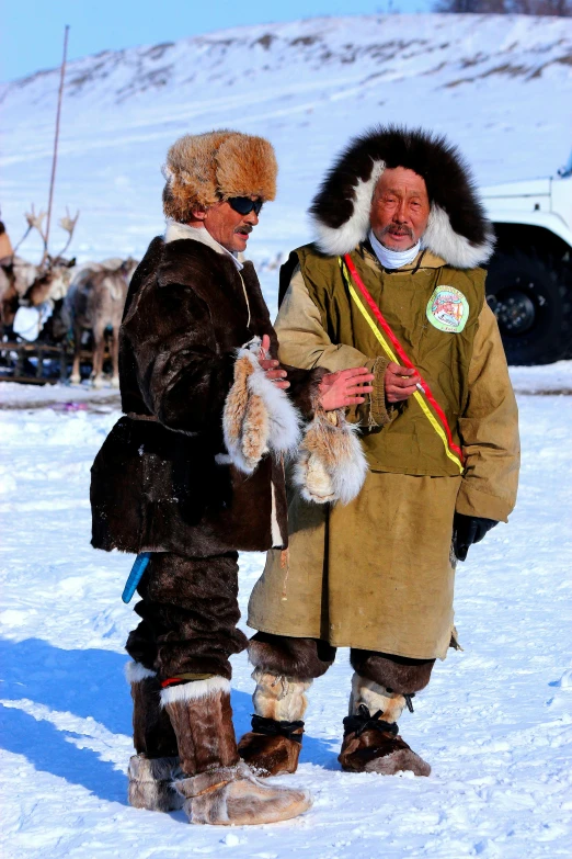 a man wearing a fur coat on top of a snow covered slope