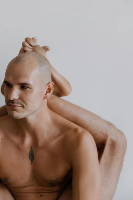 a man that is sitting in a chair with a shaved head