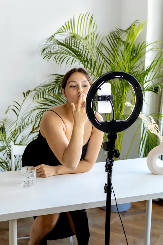the woman sits in front of the camera with her hands on her chin
