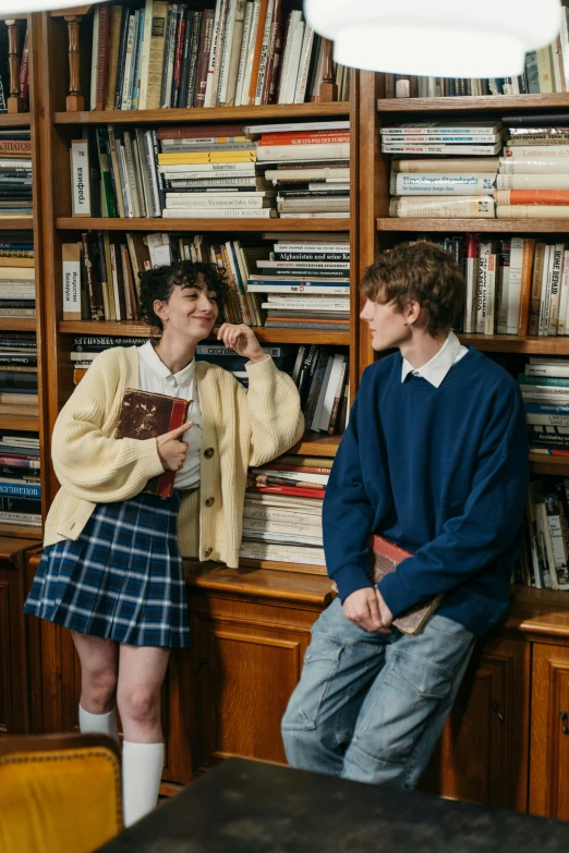 a woman and man sitting in a liry, with books all over the room