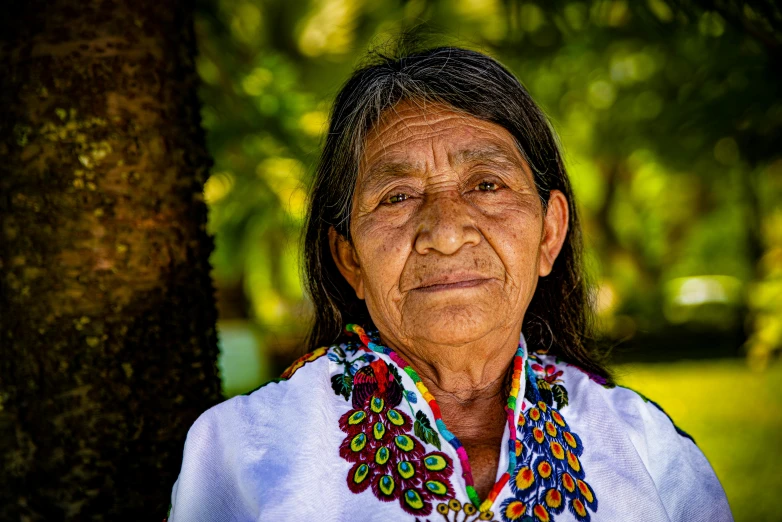 an old woman posing for the camera under trees