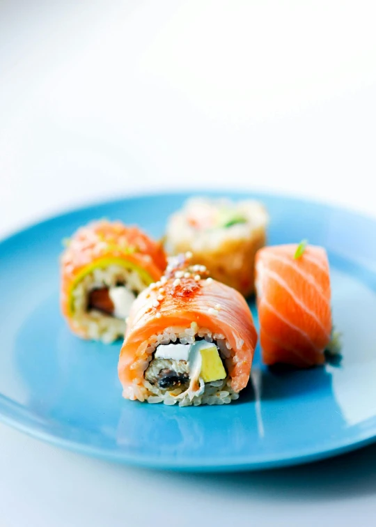 three sushi rolls are on a blue plate