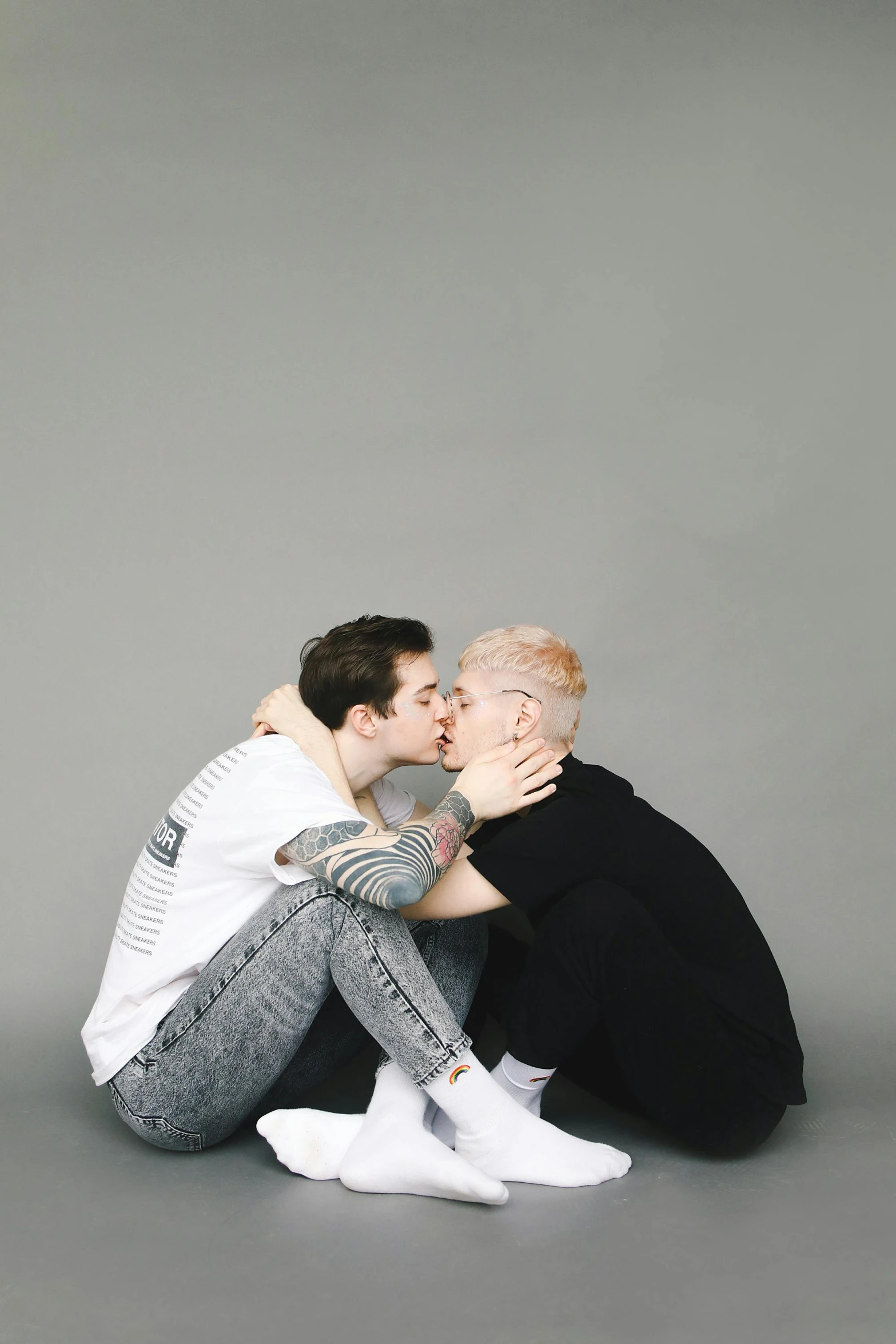 two men sit on the floor kissing