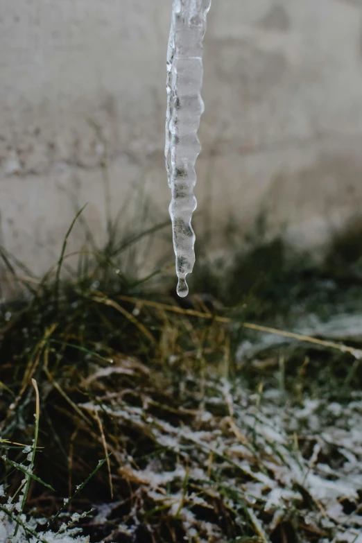 a clear icicle is hanging off the edge of a pole