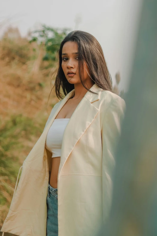 a woman in white top with a light yellow coat