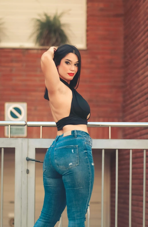 a woman is standing on the railing wearing a black top and jeans