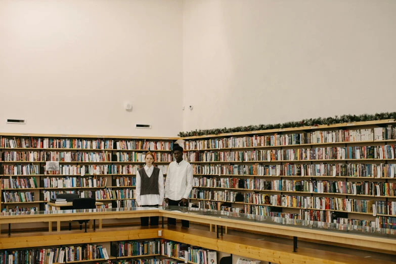 two people standing in a large room filled with books