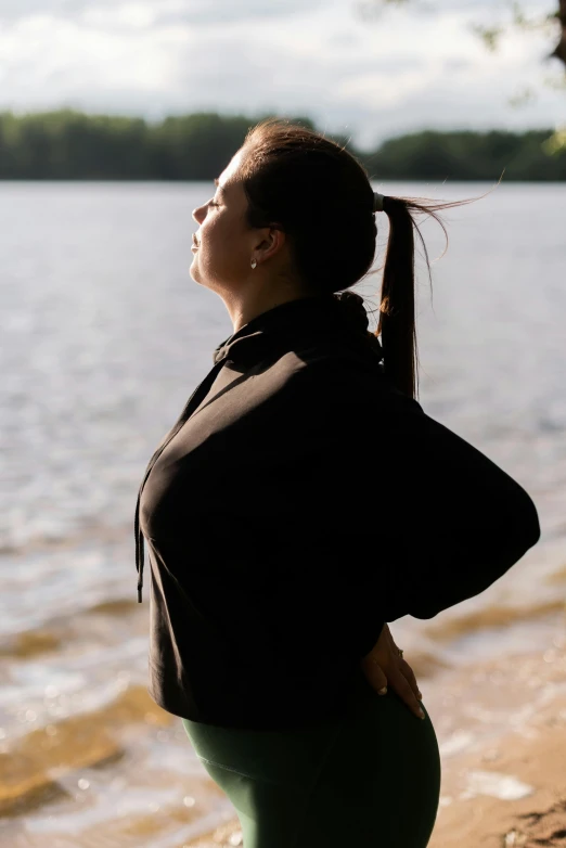 a woman standing on top of a beach next to a body of water