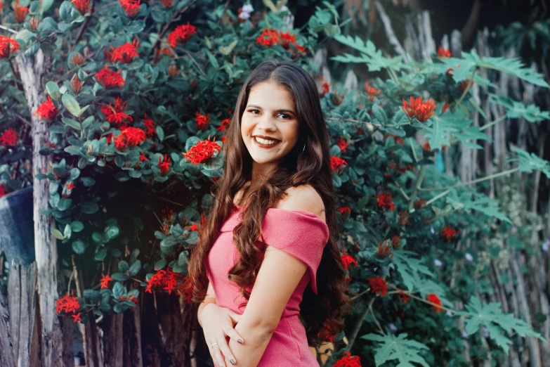 a girl in a pink dress posing next to red flowers