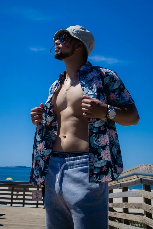 a man wearing  stands on a wooden deck overlooking the ocean