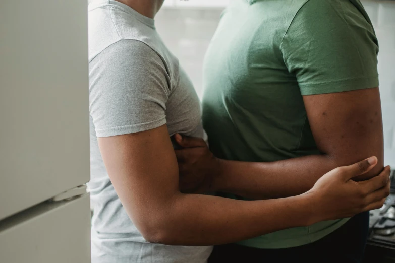 an older man hugs a younger man in a kitchen