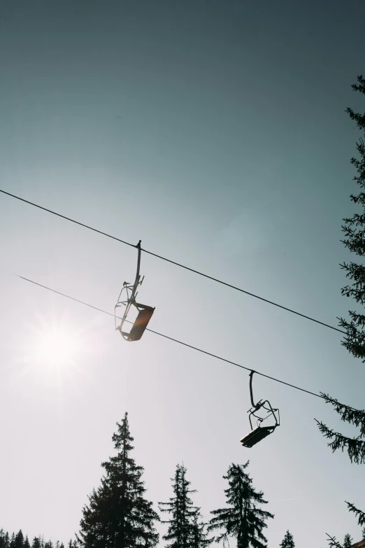 sun shines in the sky and the silhouettes of three ski lifts