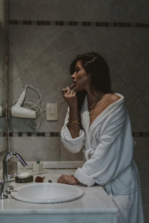 a woman brushes her teeth in the bathroom mirror