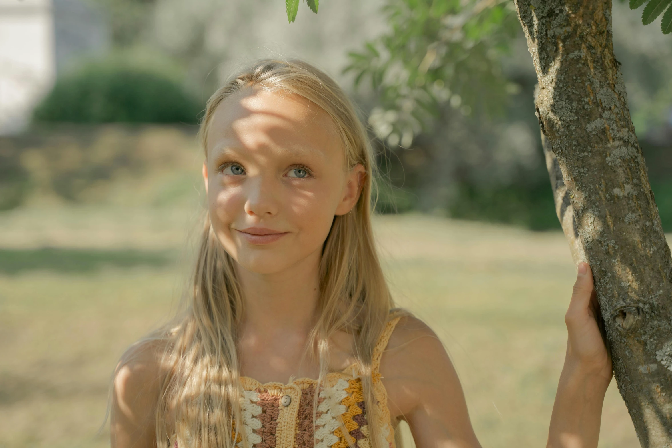 a young blond girl holding onto a tree nch