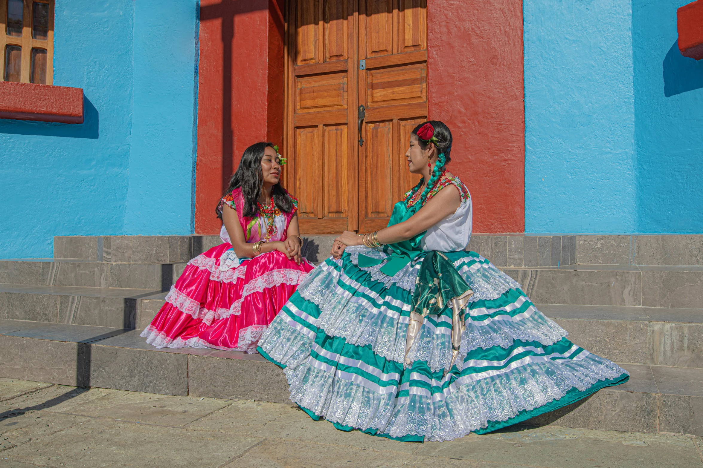 two women in colorful dresses are sitting on some steps