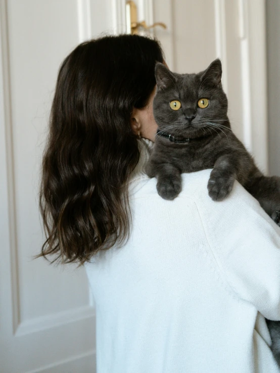 a cat being held by a person with long hair