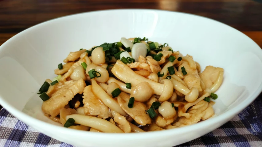 a white bowl filled with noodles and green onions