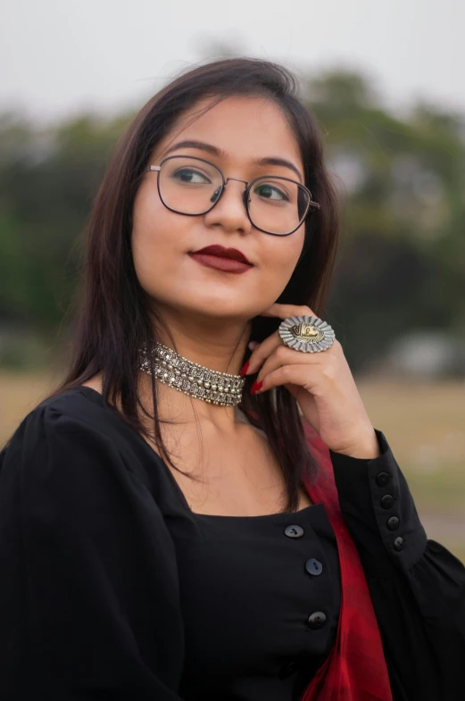 a girl wearing glasses posing with a black shirt and red scarf