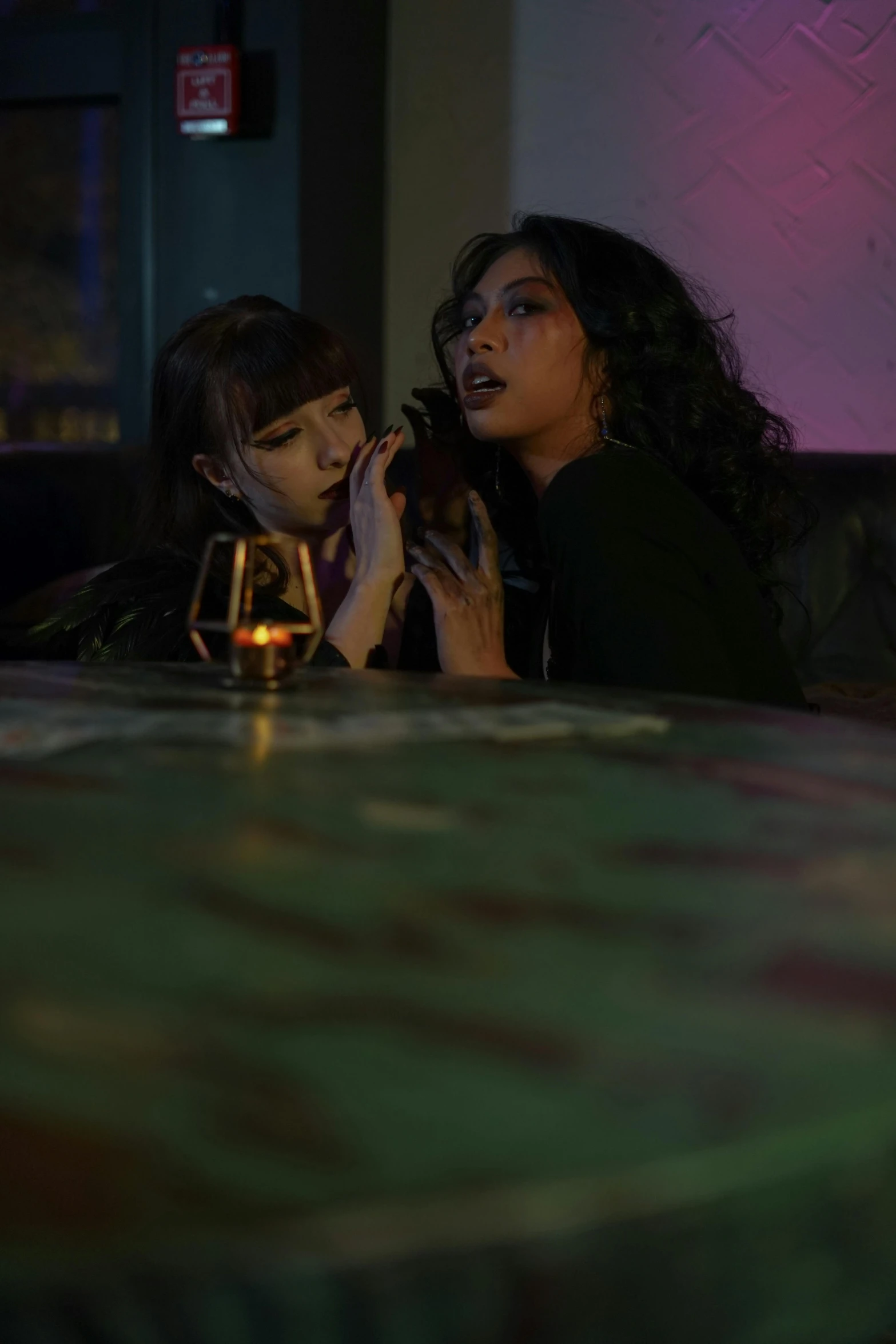 two women talking and a glass of wine sitting on a table