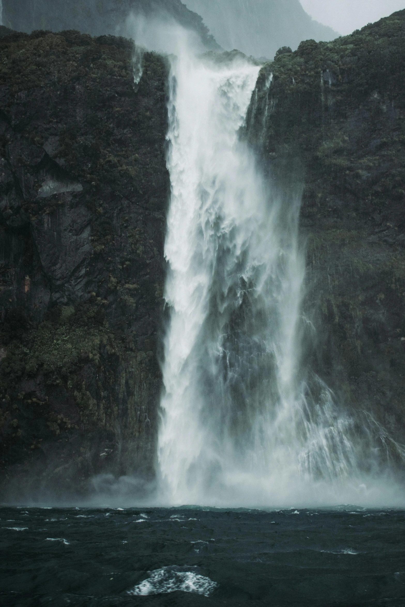 water gushing down a side of a cliff into the ocean