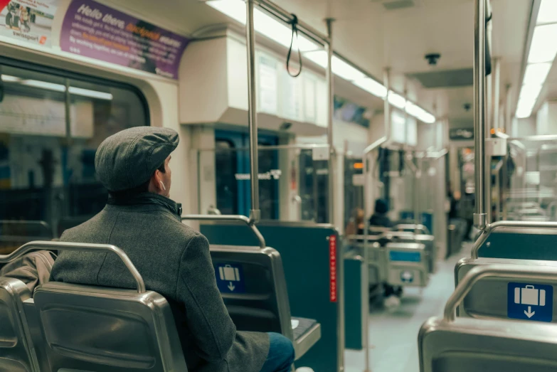 a person sitting in the subway alone wearing a hoodie